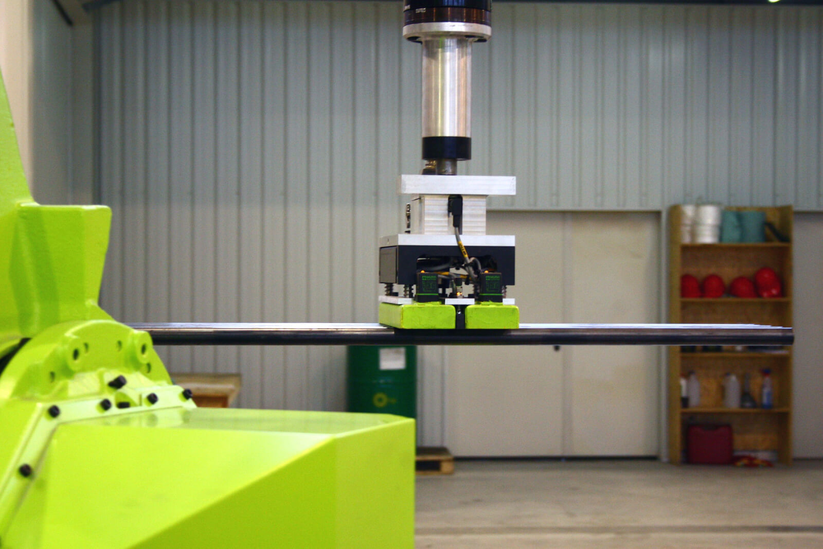 Zautomatyzowana maszyna przemysłowa z ramieniem robota trzymającym metalowy pręt. Sprzęt produkcyjny w warunkach fabrycznych.